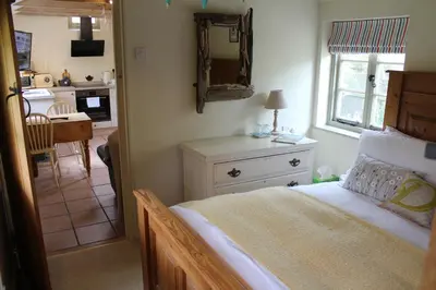 a bedroom with a bed with a dresser and a mirror at Dairy Cottage Luxury B&B in Attleborough