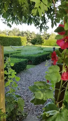 a person walking through a garden with flowers and bushes at Dairy Cottage Luxury B&B in Attleborough