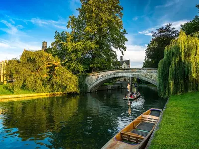 a boat on a river under a bridge at Mathus Gardens in Cambridge
