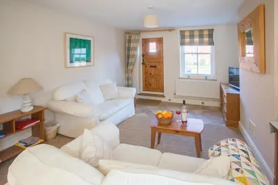 a living room with white couches and a tv at Drift In in Aldeburgh