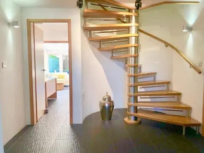 a wooden spiral staircase in a room with a living room at Laurels in Felsted