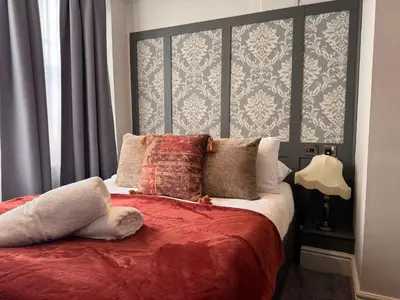 a bedroom with a bed with red sheets and pillows at Regency House in Cambridge