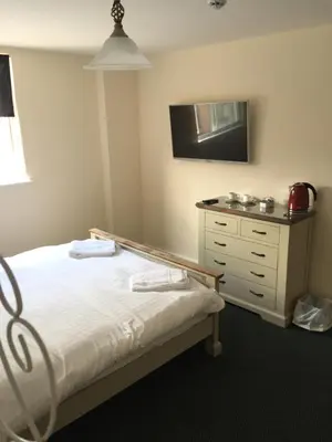 a bedroom with a bed and a dresser with a television at The Dorrington in Halstead