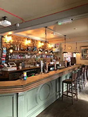 a bar with a long counter with bar chairs at The Dorrington in Halstead