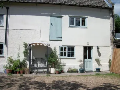 a white house with a blue door and a bench at The Walnuts Country House in West Row