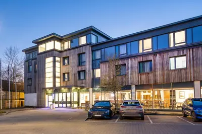 a building with cars parked in a parking lot at B&B Hotel Cambridge South in Cambridge