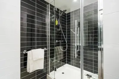a black tiled bathroom with a shower and a tub at B&B Hotel Cambridge South in Cambridge