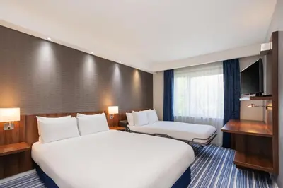 a hotel room with two beds and a flat screen tv at B&B Hotel Cambridge South in Cambridge