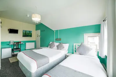 a hotel room with two beds and a table at Devine Beach Hotel, Westcliff Southend-On-Sea in Southend-on-Sea
