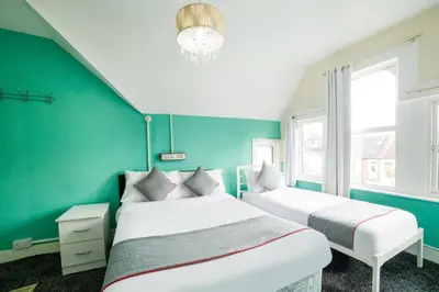 two beds in a room with green walls at Devine Beach Hotel, Westcliff Southend-On-Sea in Southend-on-Sea