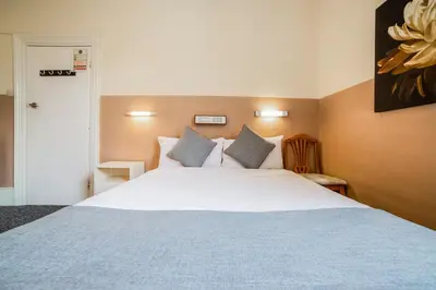 a bedroom with a large white bed with pillows at Devine Beach Hotel, Westcliff Southend-On-Sea in Southend-on-Sea