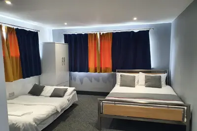two beds in a room with colorful curtains at Devine Beach Hotel, Westcliff Southend-On-Sea in Southend-on-Sea