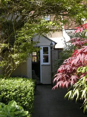 a house with a white door and some bushes at Motts Bed & Breakfast in Great Dunmow