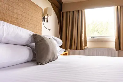 a hotel room with two beds and a window at The Mill Hotel Sudbury in Sudbury