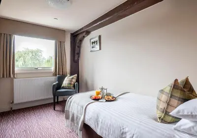 a hotel room with a bed with a tray of fruit on it at The Mill Hotel Sudbury in Sudbury