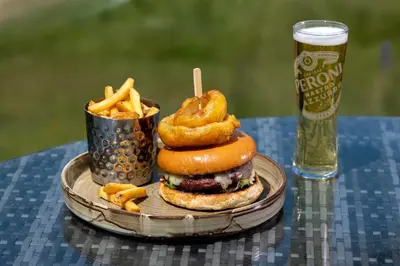 a sandwich and french fries on a table with a glass of beer at The Mill Hotel Sudbury in Sudbury