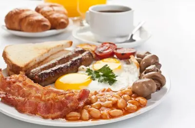 a plate of breakfast food with eggs bacon beans and a cup of coffee at The Mill Hotel Sudbury in Sudbury