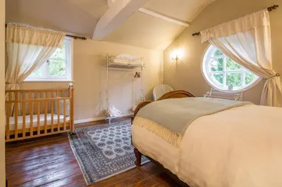 a bedroom with a bed and a crib and a window at The Domek in Ashwell
