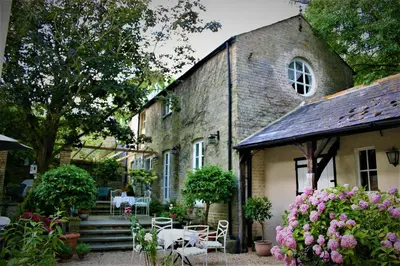 an old brick house with tables and chairs and flowers at The Domek in Ashwell