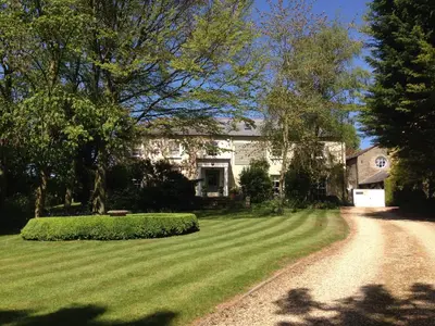 a house with a grass yard and a dirt road at The Domek in Ashwell