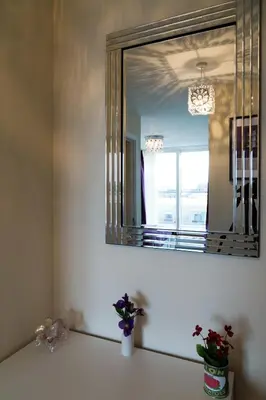a bathroom with a mirror and a sink with flowers at Contemporary & Homely Penthouse, 2 mins walk from Cambridge Station, lift access, secured gated on-site parking, self check-in, SUPER Fast WIFI, Terrace & Sleeps 6 in Cambridge