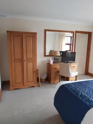 a bedroom with a bed and a desk with a television at Byerley House in Newmarket