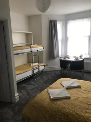 a room with two bunk beds and a table at Brunton House Guest House in Clacton-on-Sea