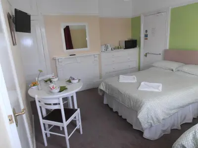 a bedroom with a bed and a table with a mirror at Brunton House Guest House in Clacton-on-Sea