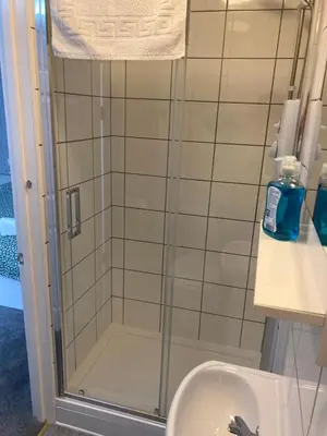 a shower with a glass door next to a sink at Brunton House Guest House in Clacton-on-Sea