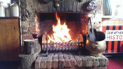 a brick fireplace with a fire in it at The Red Lion in Cambridge