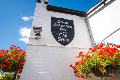 a sign on the side of a building with flowers at The Red Lion in Cambridge