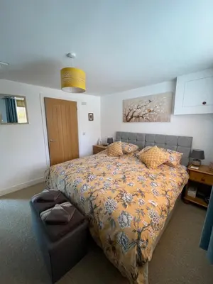 a bedroom with a bed and a chair at Chestnut Cottage in East Bergholt
