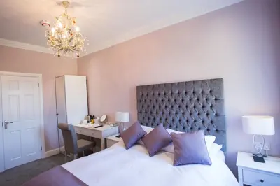 a bedroom with a bed and a desk and a chandelier at B&B Downham Hall in Wickford