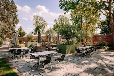a patio with tables and chairs in a garden at B&B Downham Hall in Wickford