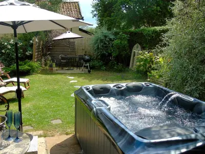 a hot tub in a yard with an umbrella at The Coach House - Ukc2365 in Watton