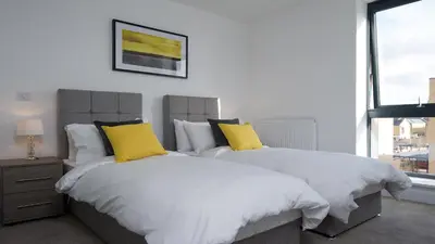 two beds with yellow pillows in a bedroom at Tailored Stays - De Havilland House in Cambridge