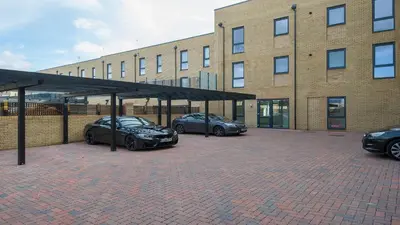 three cars parked in front of a brick building at Tailored Stays - De Havilland House in Cambridge