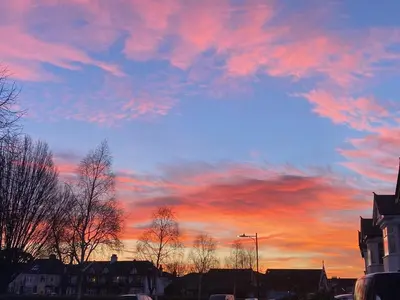 a sunset with a colorful sky with trees and buildings at Pebbles Guest House in Southend-on-Sea