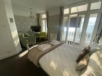 a bedroom with a large bed and a living room at Pebbles Guest House in Southend-on-Sea