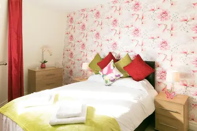 a bedroom with a bed with a pink floral wall at Penthouse 5 mins walk to City Centre & Colleges with Balcony & Sleeps 6 in Cambridge