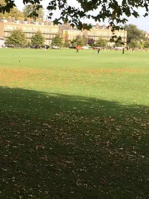 a green field with people in a park with a building at Penthouse 5 mins walk to City Centre & Colleges with Balcony & Sleeps 6 in Cambridge
