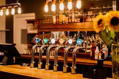 a bar with a row of wine glasses on a counter at The Cricketers Arms in Quendon