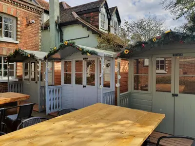 a patio with a wooden table in front of a house at The Cricketers Arms in Quendon