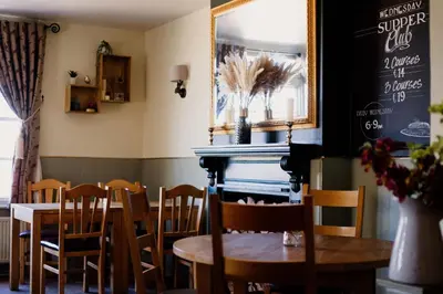a dining room with a table and chairs and a chalkboard at The Cricketers Arms in Quendon