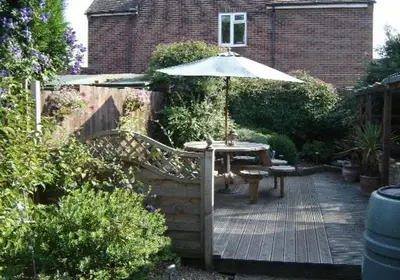 a wooden deck with a table and an umbrella at Leverton House in Cambridge