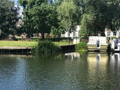 a boat is docked at a dock on a river at Pike & Eel Hotel and Marina in Needingworth