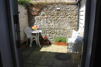 a patio with a stone wall and a table and chairs at Seaside Fisherman Cottage Aldeburgh in Aldeburgh