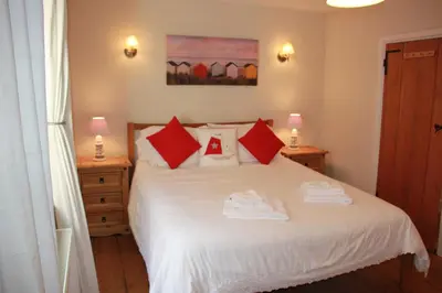 a bedroom with a white bed with red pillows at Seaside Fisherman Cottage Aldeburgh in Aldeburgh