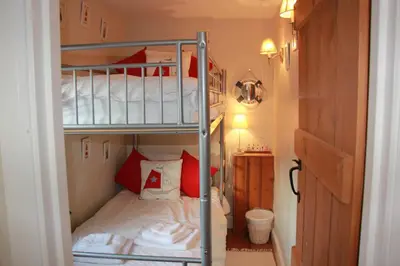 a bedroom with two bunk beds with red and white pillows at Seaside Fisherman Cottage Aldeburgh in Aldeburgh