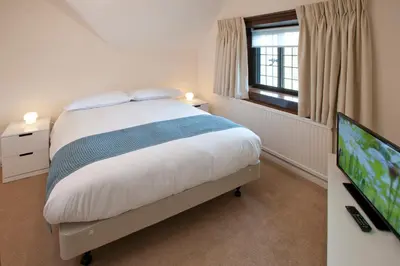 a bedroom with a bed and a flat screen tv at Madingley Hall in Cambridge
